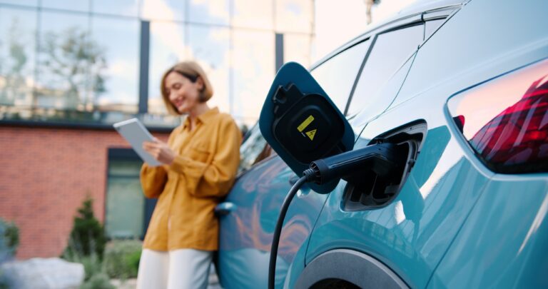 Woman standing by an EV charging representing interest in EV in Australia